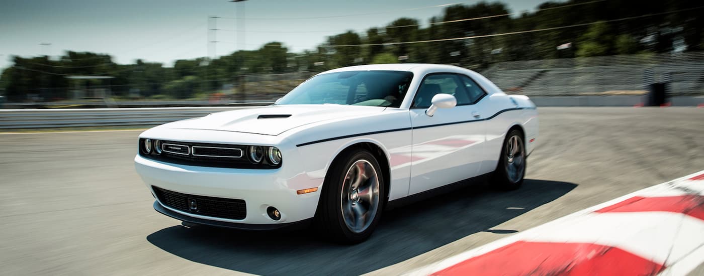 A white 2015 Dodge Challenger is shown driving on a track.