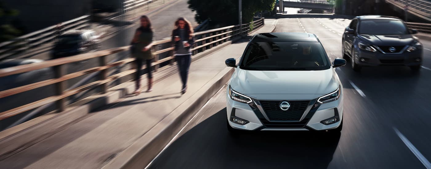 A white 2021 Nissan Sentra is shown from the front driving on a busy highway.