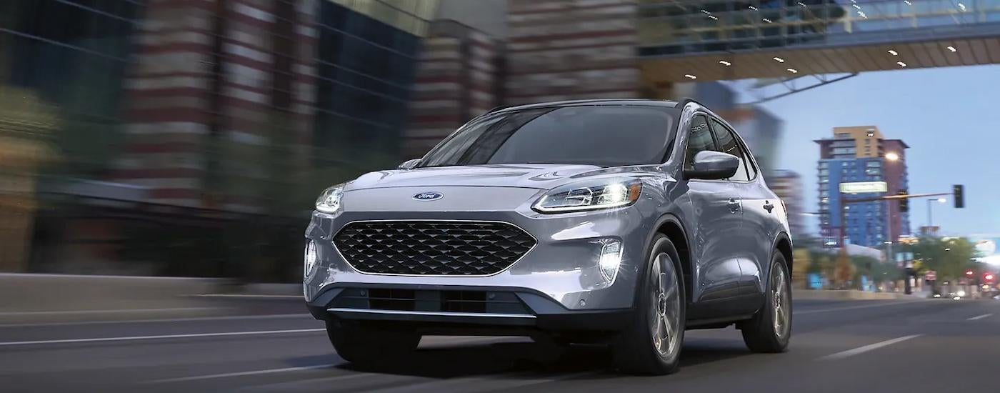 A silver 2022 Ford Escape Hybrid is shown driving on a city highway.