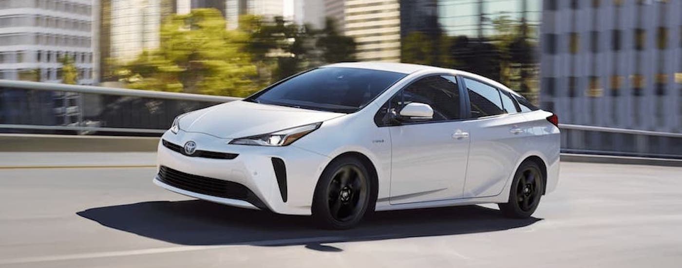 A white 2020 Toyota Prius is shown form the side on a city street.
