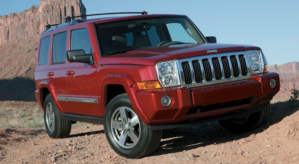 A red 2008 Jeep Commander off-roading on a rocky desert trail after leaving a used Jeep dealer.