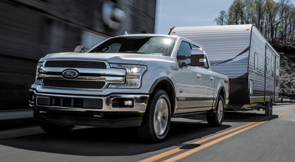 A white 2018 Ford F-150 towing a trailer across a bridge.