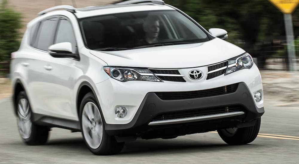 A white 2015 Toyota RAV4 driving on a winding road.