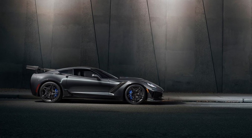 A grey 2019 Chevy Corvette ZR1 parked in front of a concrete wall at night.