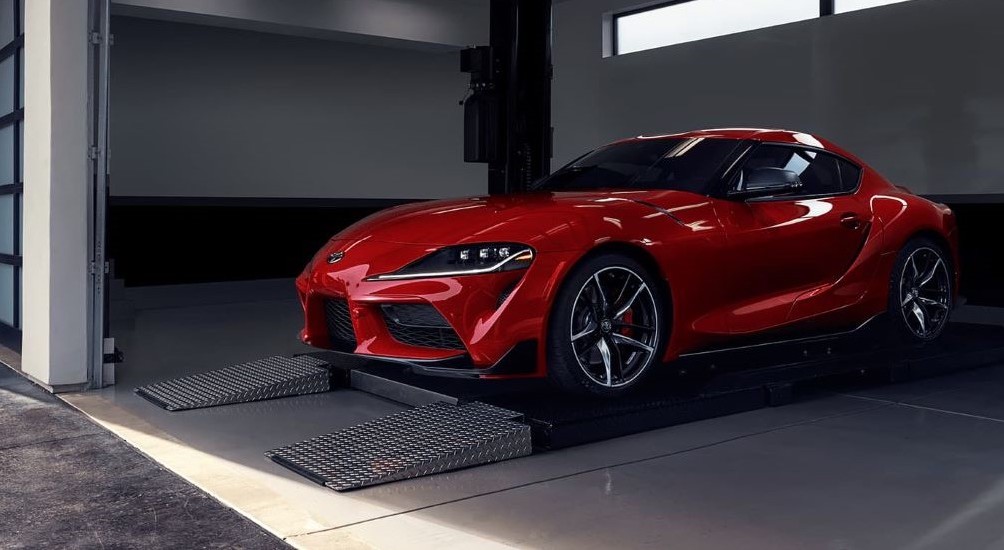 A red 2020 Toyota GR Supra parked in the garage of a used sports car dealer.