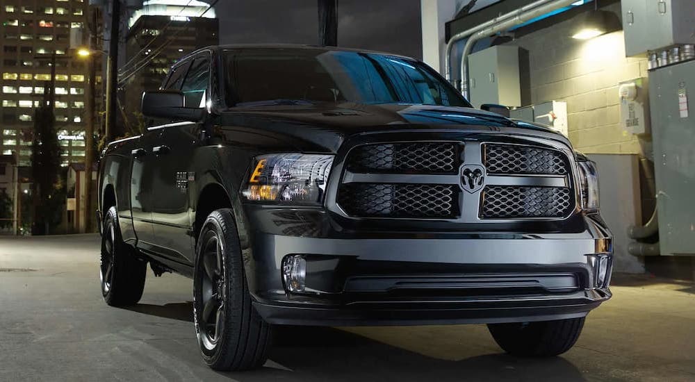 A black 2022 Ram 1500 parked in a city alley at night after viewing used trucks for sale.