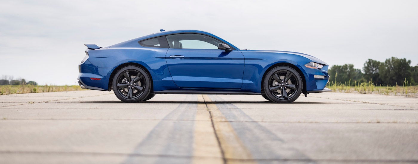 A blue 2022 Ford Mustang Ecoboost is shown from the side while parked on a runway.