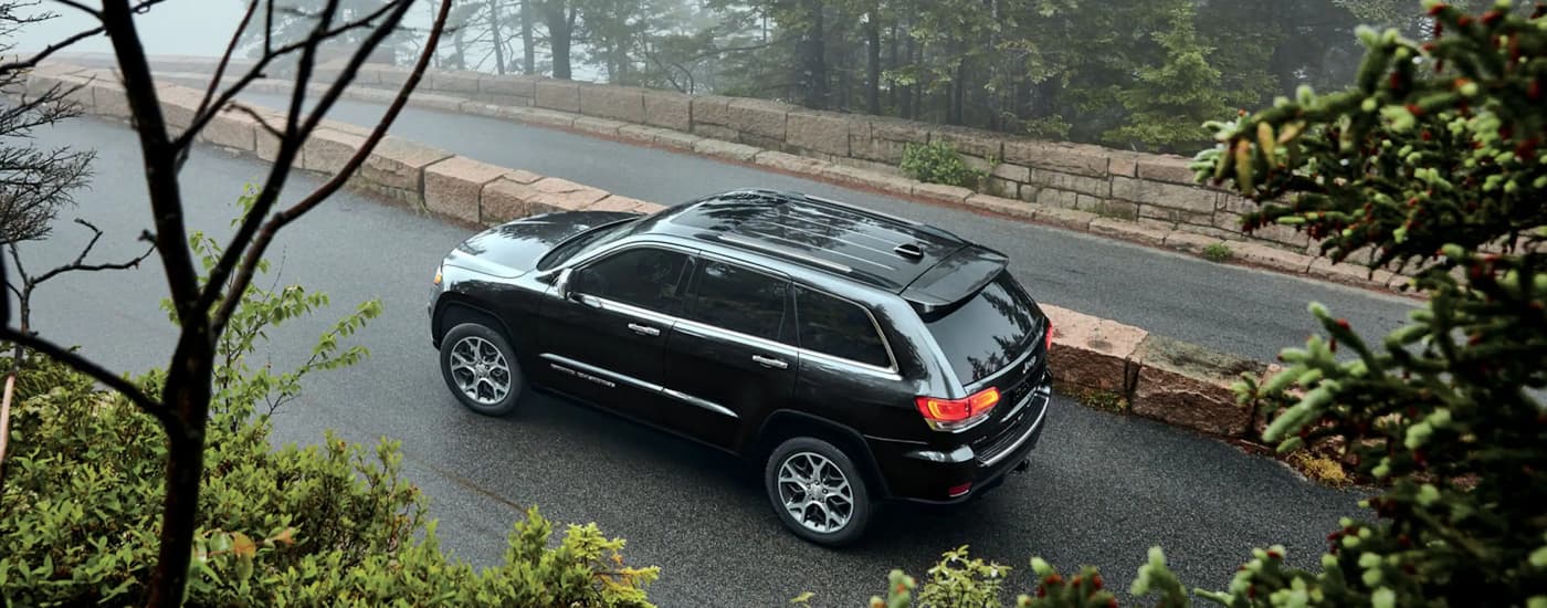 A black 2022 Jeep Grand Cherokee WK is shown driving up a paved hilly road.