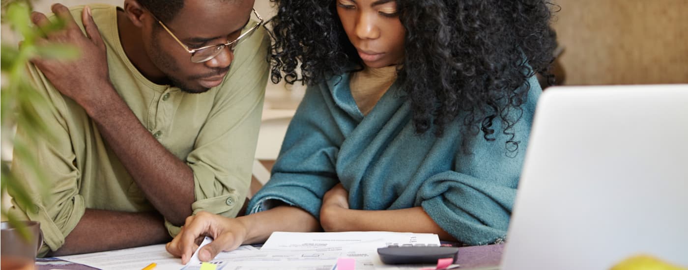 A couple is shown going over paperwork after deciding to sell their car.