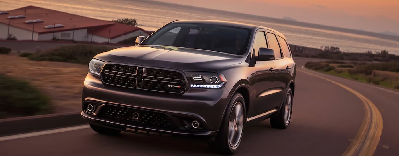 A grey 2014 Dodge Durango is shown driving on a winding road after leaving a used Dodge dealer.
