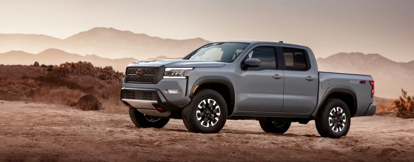 A grey 2022 Nissan Frontier is shown from the side parked in a desert area.