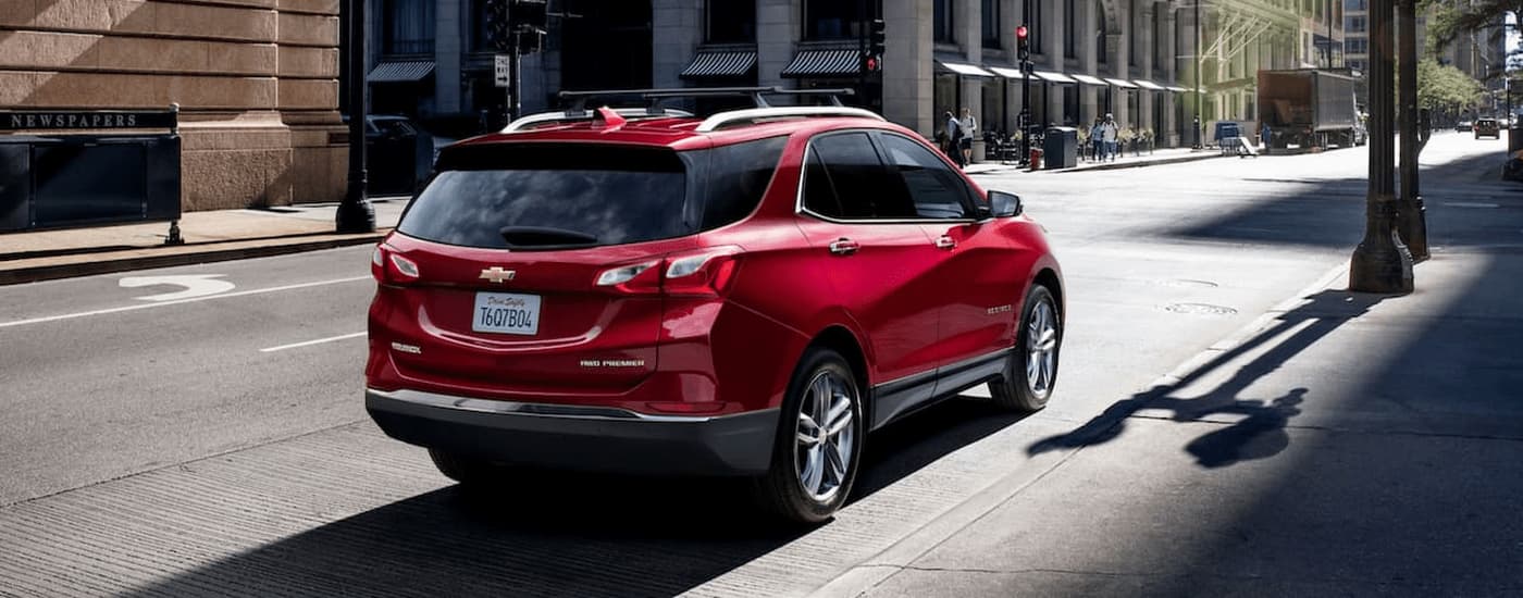 A red 2021 Chevy Equinox is shown parked on the side of a city street after leaving a used car dealer near Plainfield.