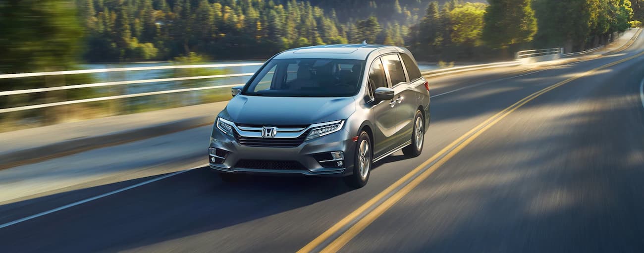 A grey 2020 Honda Odyssey is shown driving on an open highway.