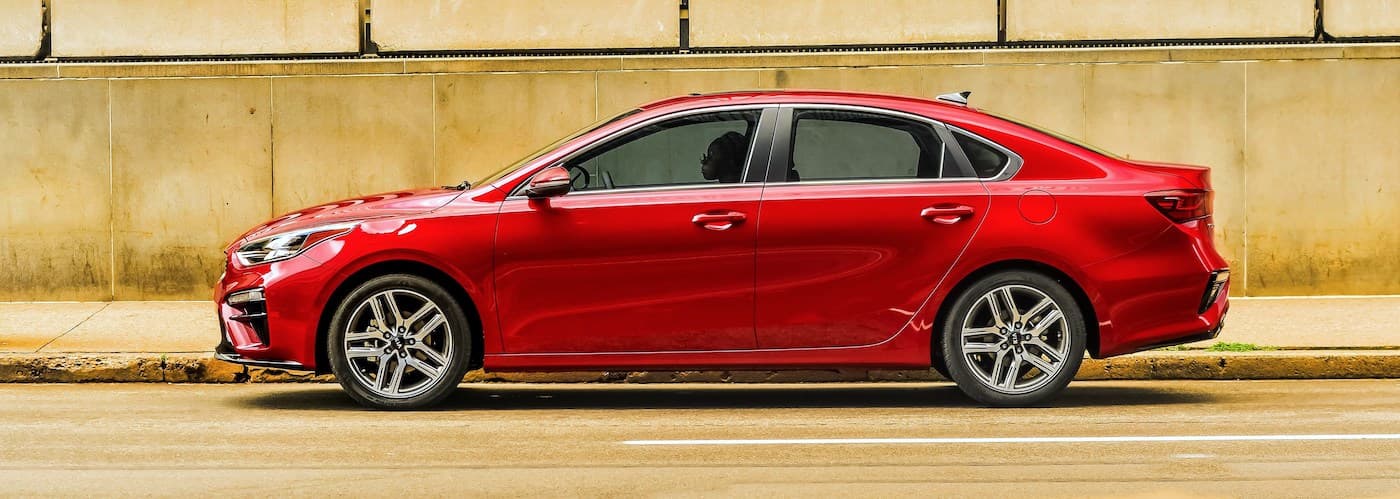 A red 2020 Kia Forte is shown from the side driving on a city street after leaving a used car dealer near Shelbyville.