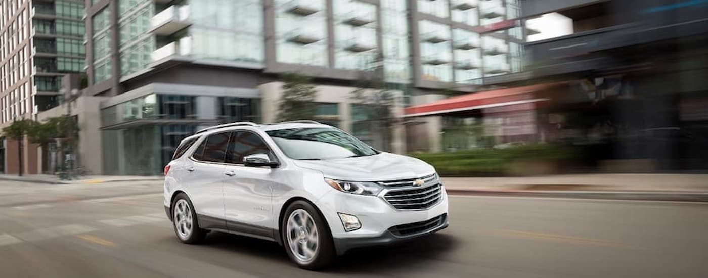 A white 2018 Chevy Equinox is shown driving on a city street.