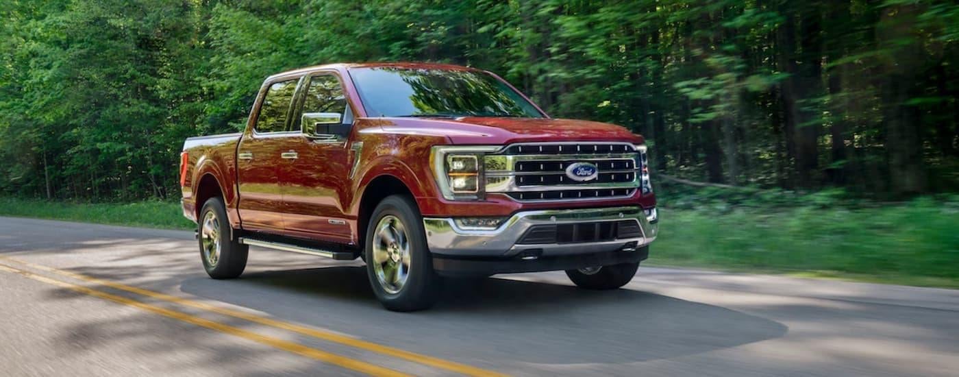A red 2021 Ford F-150 is shown driving on an open road.