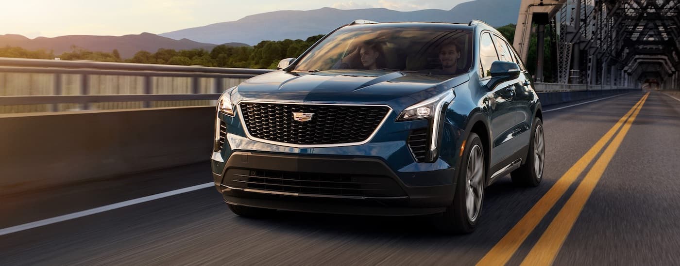 A blue 2020 Cadillac XT4 is shown driving on a bridge.