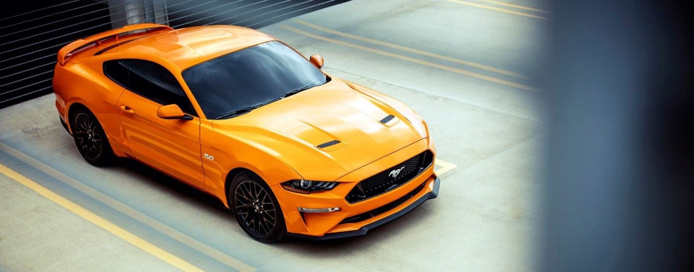 An orange 2018 Ford Mustang GT is shown in a parking lot.