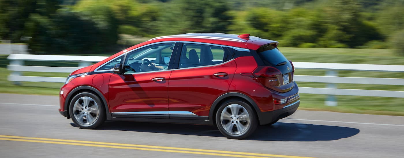 A red 2020 Chevy Bolt EV is shown from the side driving on an open road.