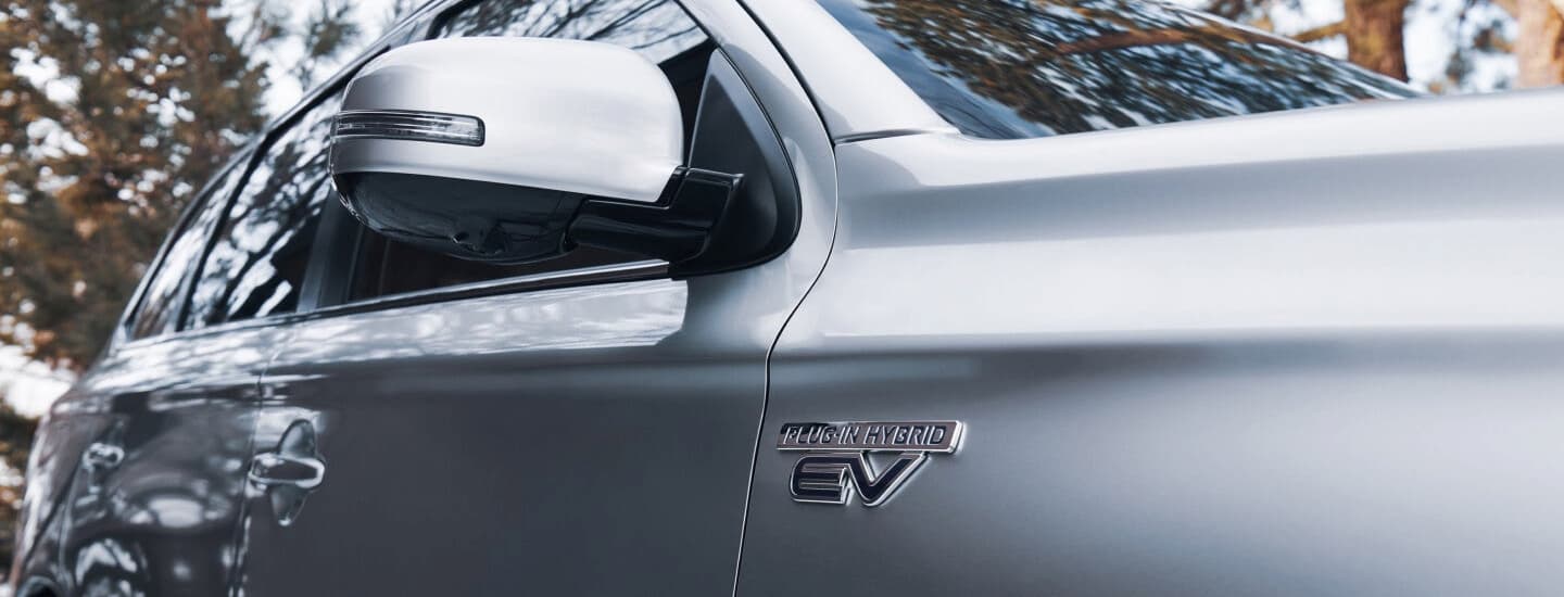 A close up of the side of a silver 2022 Mitsubishi Outlander PHEV is shown.