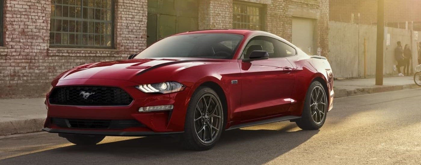 A red 2022 Ford Mustang is shown parked on the side of a street after leaving a used sports car dealer.