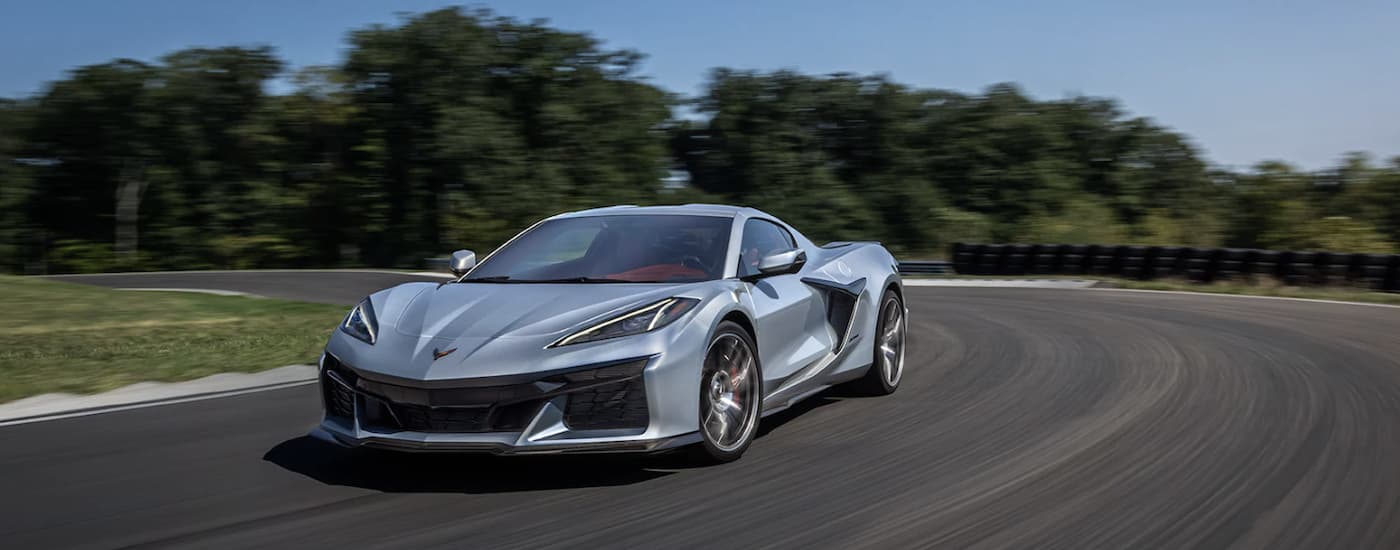 A silver 2023 Chevy Corvette Z06 is shown driving on a track after leaving a used sports car dealer.