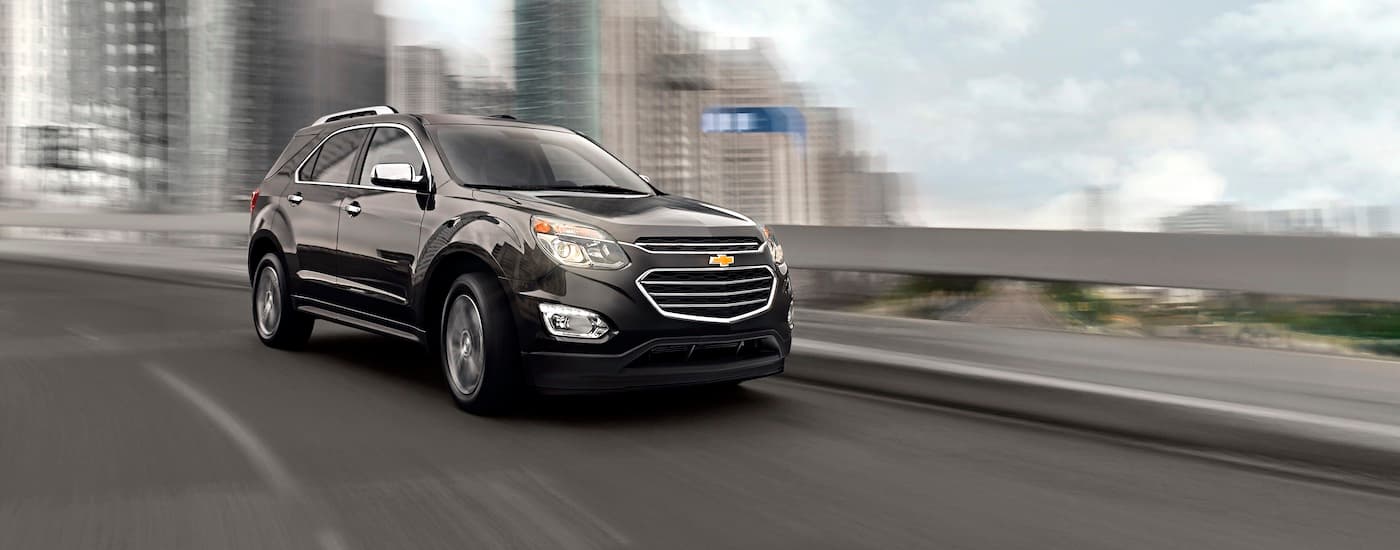 A black 2016 Chevy Equinox is shown driving on a city street.