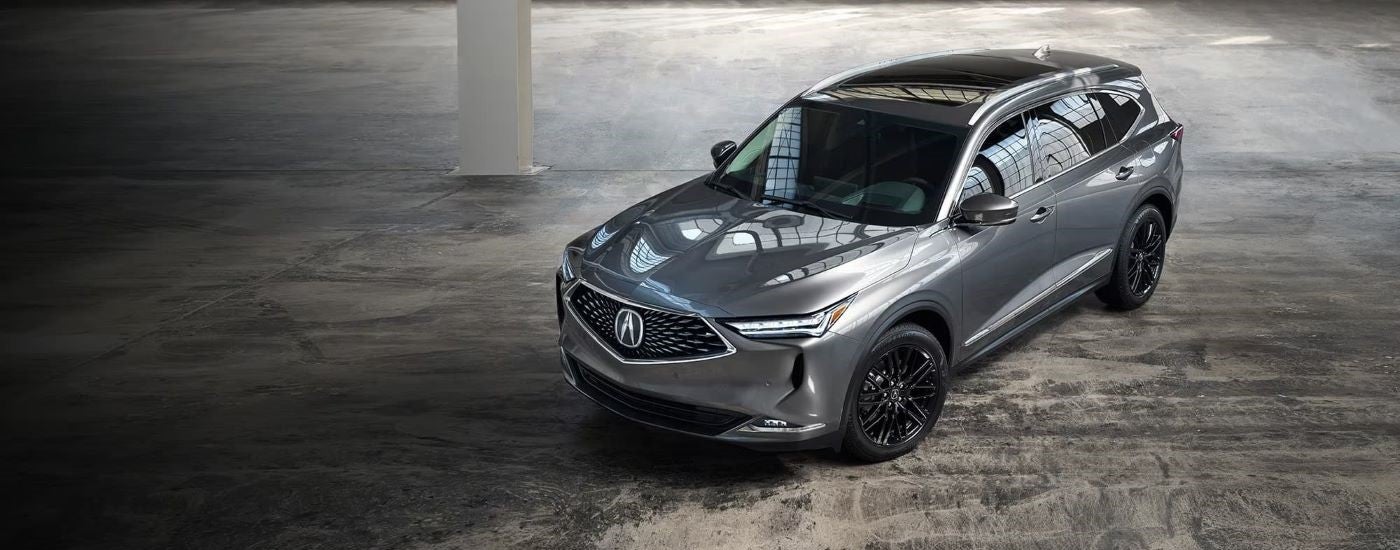 A silver 2021 Acura MDX is shown in a modern gallery.