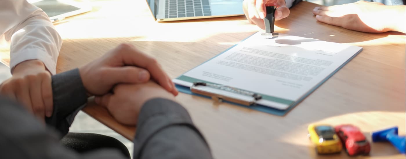 A person is shown filing paperwork for a used car for sale they want to buy.