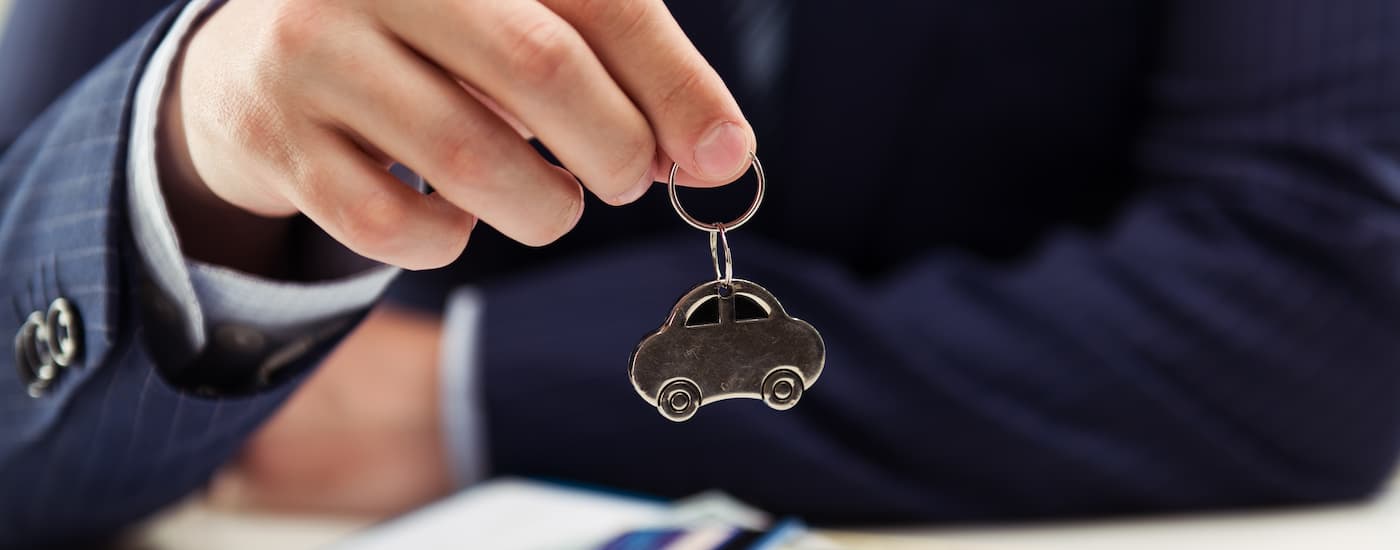 A salesman is shown dangling a car keychain at a dealership.
