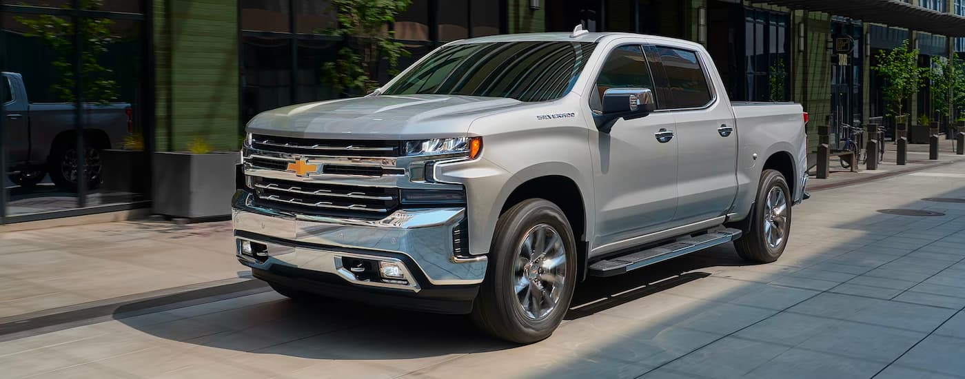 A silver 2019 Chevy Silverado 1500 is shown driving on a city street.