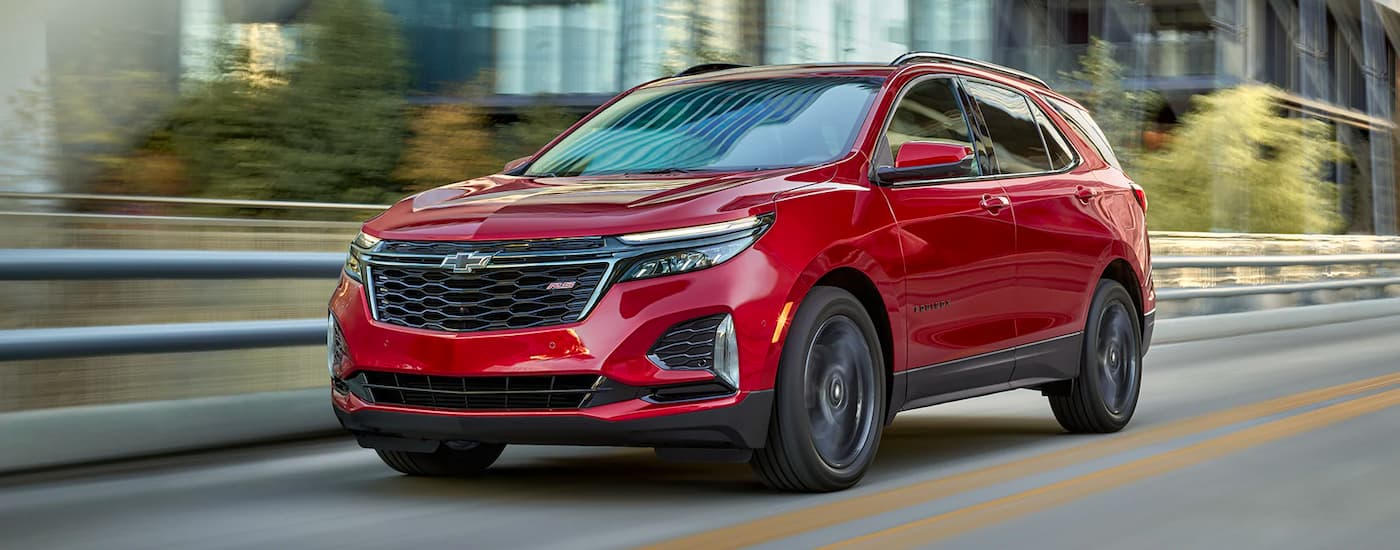 A red 2022 Chevy Equinox RS is shown driving on a city street after leaving a used Chevy dealer.