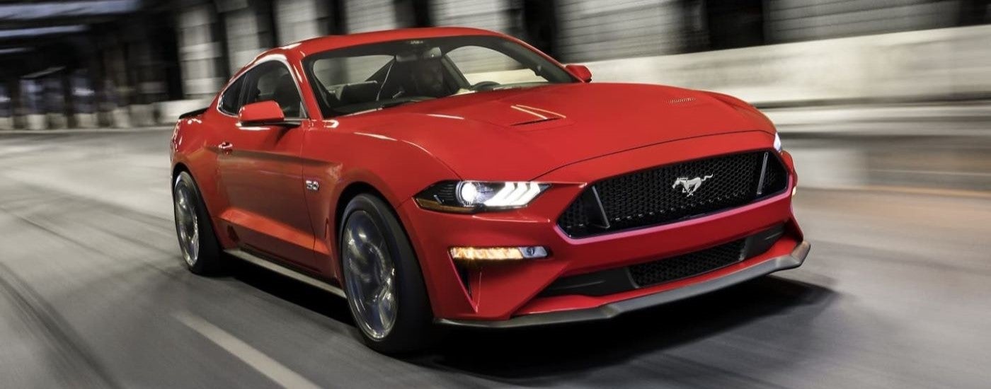 A red 2021 Ford Mustang GT is shown driving though a tunnel.